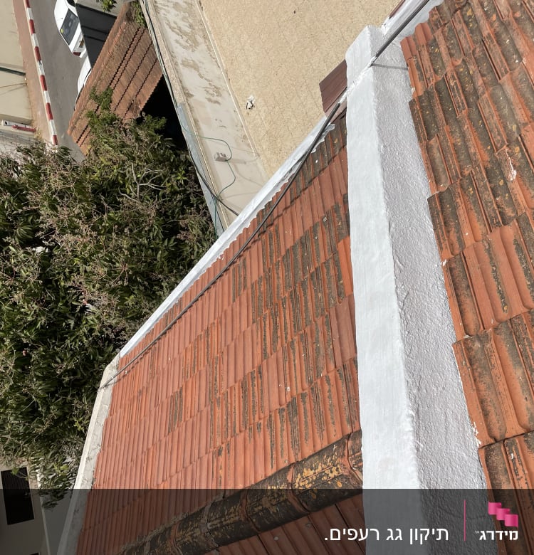 גג רעפים אדומים עם קיר לבן במרכז